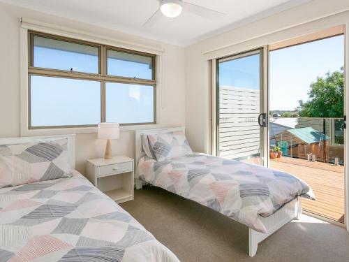 a bedroom with two beds and a balcony at The Bay House in Corinella