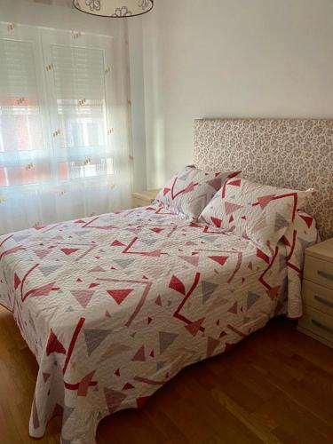 um quarto com uma cama com um edredão vermelho e branco em Piso Vista os castelos em Viveiro