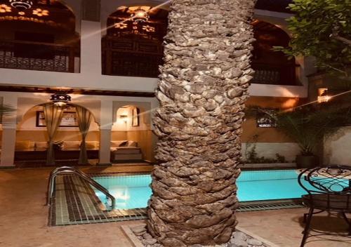 un pilier en pierre dans le hall de l'hôtel avec une piscine dans l'établissement Riad Palmier, à Marrakech