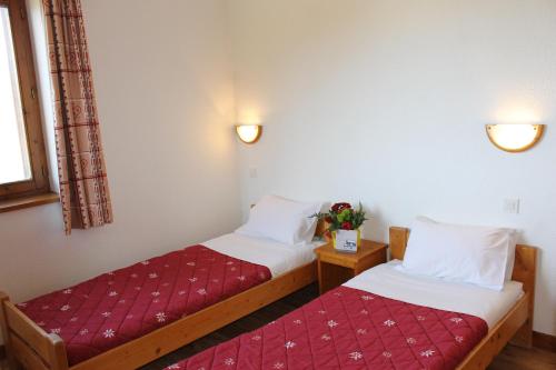 2 bedden in een kamer met een rode sprei bij Résidence Saboia B54 Clés Blanches Courchevel in La Tania