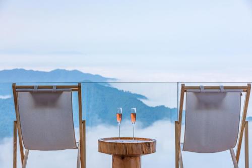 two glasses of wine on a table and two chairs at Rice View Lodge in Longsheng