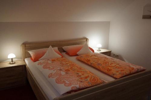 a bedroom with a bed with two pillows and two lamps at Ferienwohnung Pietzavka in Wiesenfelden