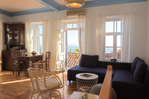un soggiorno con divano blu, tavolo e finestre di cherry's home a Glossa