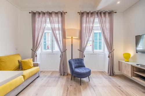 a living room with a yellow couch and a blue chair at Cayres Suites Surdo in Funchal