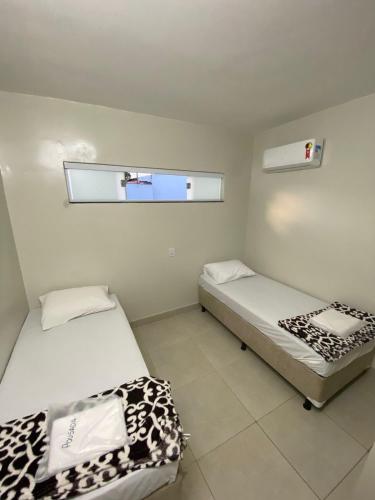 2 camas en una habitación pequeña con espejo en Pousada Dona Lia, en Uberlândia