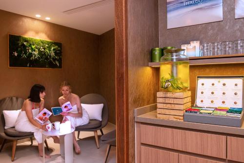 two women sitting in a hotel room with a baby at Radisson Blu Hotel, Rouen Centre in Rouen