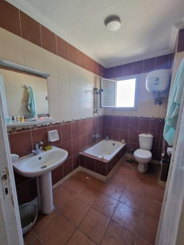 La salle de bains est pourvue d'une baignoire, d'un lavabo et de toilettes. dans l'établissement Panoramic Sea View ZAMZM Flat miami FAMILY شقة فندقية زمزم بانورما بشاطئ ميامي - الاسكندرية صف اول مباشر علي بحر - عائلات فقط, à Alexandrie