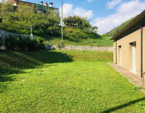 a yard with green grass and a building and a hill at Ostello La Sosta in Contrada Anselmi