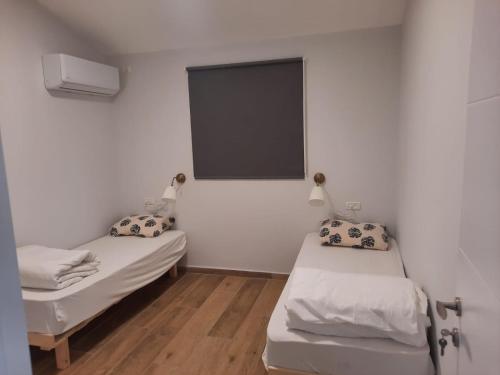 twee bedden in een kleine kamer met een raam bij בזלת וגיר in Avnei Eitan