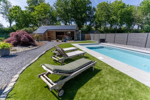 a swimming pool with two lounge chairs next to a yard at Bed & Breakfast 't Vèèrke in Dilsen-Stokkem