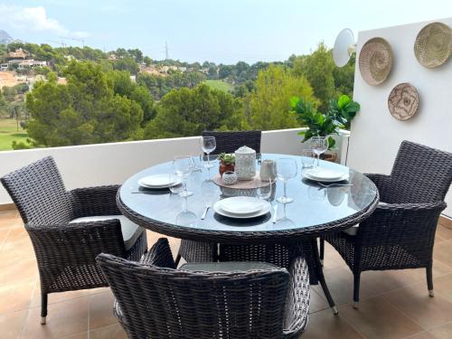 uma mesa de vidro e cadeiras numa varanda em Ama Vida Altea apartment with panoramic view em Altea