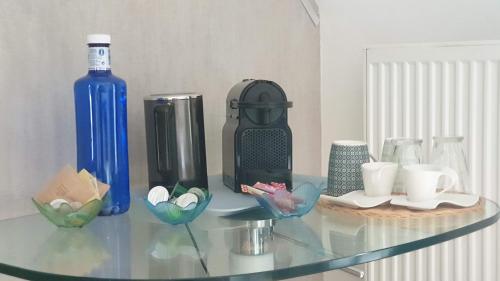 a glass table with a blue bottle and some cups at Chambre Executive Luxe et Confort pour vos Séjours in Schweighouse-sur-Moder