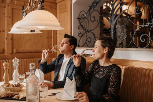 a man and woman sitting at a table drinking wine at Alpina Wagrain in Wagrain