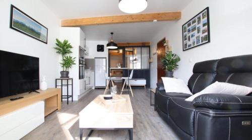 un salon avec un canapé noir et une télévision dans l'établissement Le Saint Pierre Quartier Historique d'Oloron Sainte Marie, à Oloron-Sainte-Marie