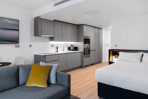 a room with a bed and a couch and a kitchen at CitySuites 2 Aparthotel in Manchester