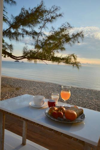 - une table avec une assiette de nourriture et de boissons sur la plage dans l'établissement Sanae Beach Hua Hin, à Khao Tao