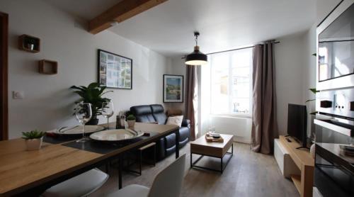 un salon avec une table à manger et un salon avec un canapé dans l'établissement Le Saint Pierre Quartier Historique d'Oloron Sainte Marie, à Oloron-Sainte-Marie