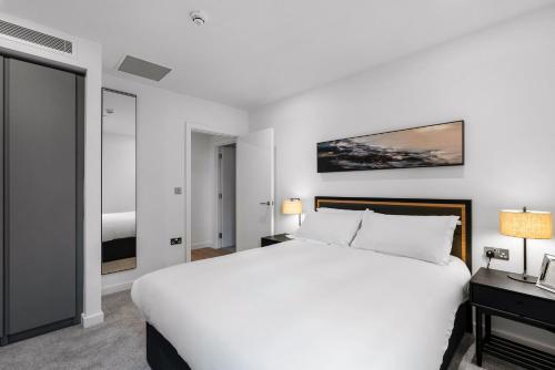 a white bedroom with a large bed and a bed sidx sidx sidx sidx at CitySuites 2 Aparthotel in Manchester