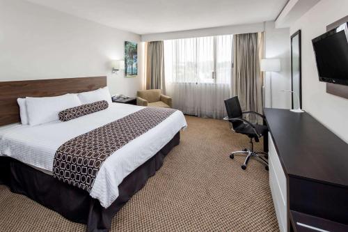 a hotel room with a bed and a flat screen tv at Wyndham Executivo Culiacan in Culiacán