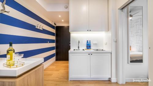 a kitchen with white cabinets and blue and white stripes at Apartament 117 HVILE in Gdańsk