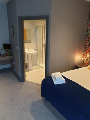 a bedroom with a bed and a bathroom with a sink at The Strutt Arms in Belper