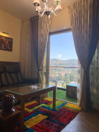 a living room with a table and a large window at Beverly villa in Ooty