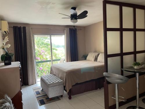 a bedroom with a bed with a ceiling fan and a window at Cityscape at Chelsea Manor / New Kingston Studio! in Kingston
