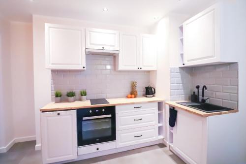 a kitchen with white cabinets and a black oven at Old Town Apartments Sandomierz in Sandomierz