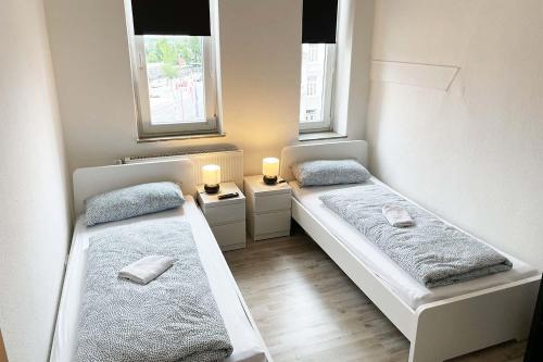 two beds in a small room with two windows at Work & Stay im Herzen von Celle mit TV und WLAN in Celle