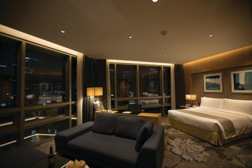 a bedroom with a bed and a couch in front of a window at Holiday Inn Incheon Songdo by IHG in Incheon