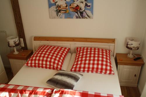 a bed with two red and white checked pillows on it at Alpfee Lechtal in Bach