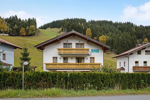 a white house with wooden balconies on a hill at Haus Lowe Appartement 2 Stock Nr 4 in Filzmoos