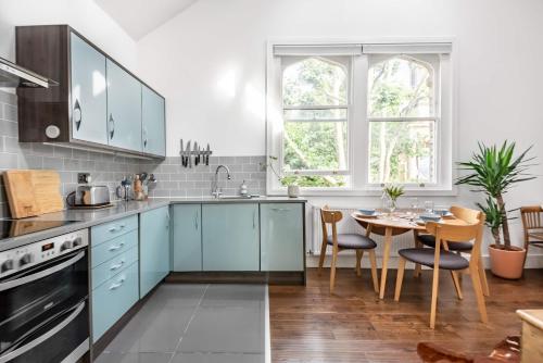 a kitchen with blue cabinets and a table with chairs at Loft Apartment in Historic Building in Quiet Central Setting in Bristol