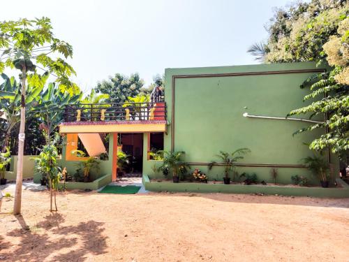 a green building with a balcony on the side of it at BANANA FARM HOUSE in Hampi