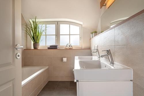 a bathroom with a sink and a tub and a window at Ferien-im-Duenenhaus-Ole in Glowe