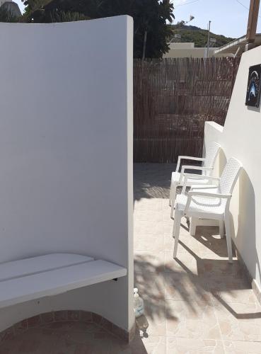 two white chairs and a bench on a patio at Delphini Studios - for the disabled in Kefalos
