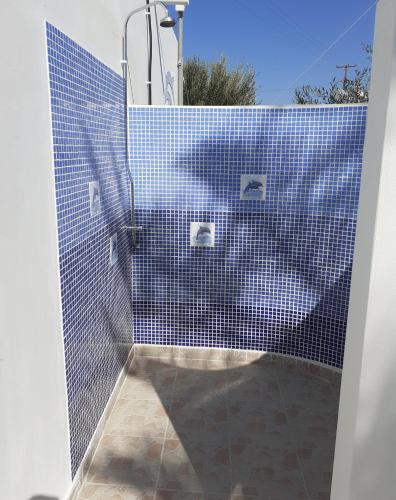 a bathroom with a blue tiled shower with a toilet at Delphini Studios - for the disabled in Kefalos