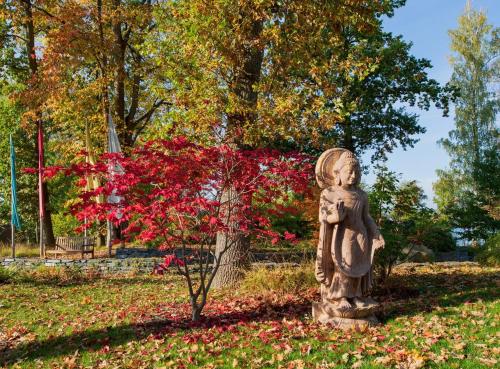 a statue in a park with a red tree at SUKHAVATI Apartments in Bad Saarow