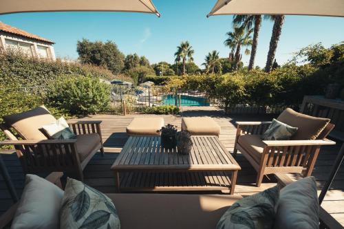un patio avec une table et des chaises et une piscine dans l'établissement Van der Valk Hotel Le Catalogne Saint Aygulf, à Saint-Aygulf