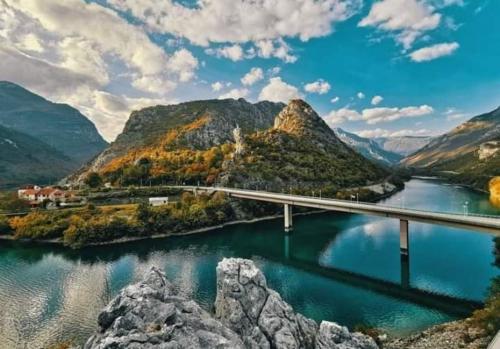un puente sobre un río con montañas en el fondo en Kuća Lavanda, en Drežnjak