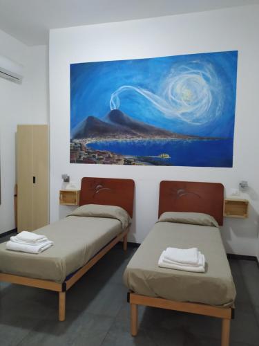ナポリにあるDomus 19の壁に絵画が飾られた部屋のベッド2台