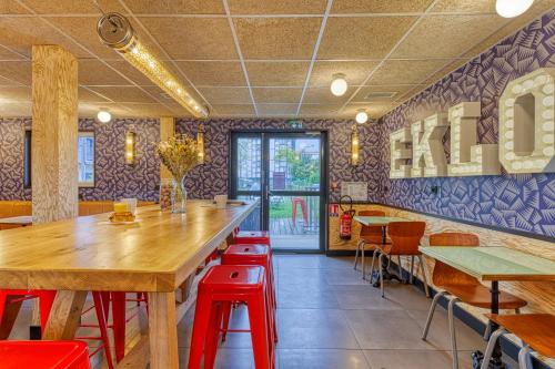 a restaurant with wooden tables and red stools at Eklo Hotels Le Havre in Le Havre