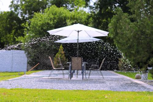 a table and chairs under an umbrella in the rain at La Capucine in Kroonstad