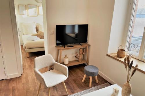 uma sala de estar com uma televisão e uma cadeira em L'amiral n3 T2 nouvelle ville ByLocly em Lorient