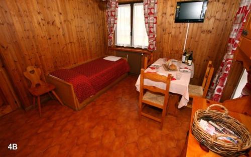 a bedroom with a bed and a table and a television at Champoluc Apartment in Champoluc