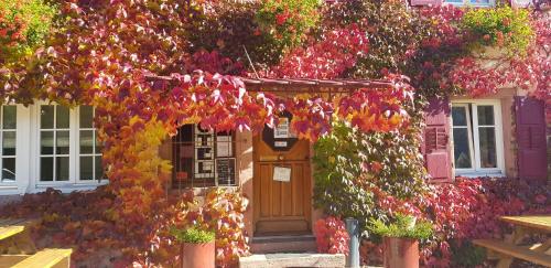 a building covered in flowers with a wooden door at Hôtel du Haut Koenigsbourg- entre vignes et château in Thannenkirch