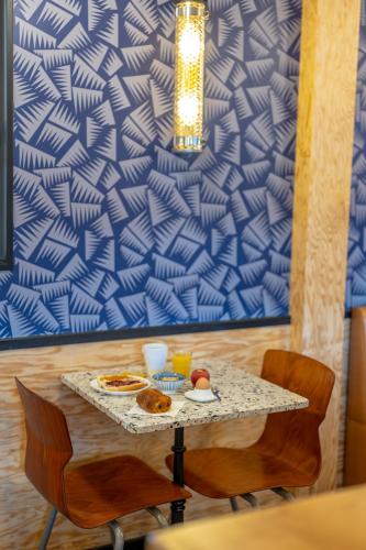 a table with two chairs and a table with food on it at Eklo Hotels Le Havre in Le Havre