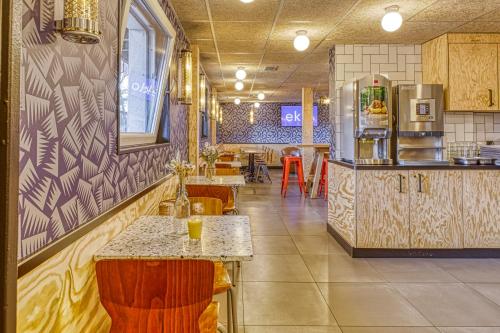 a restaurant with a counter and tables and chairs at Eklo Hotels Le Havre in Le Havre