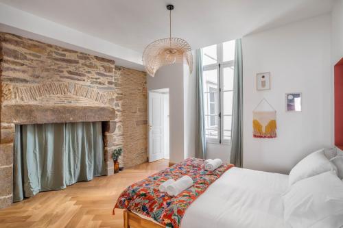 une chambre avec un grand lit et un mur de briques dans l'établissement BEAUTÉ - Appartement chaleureux et moderne, à Rennes