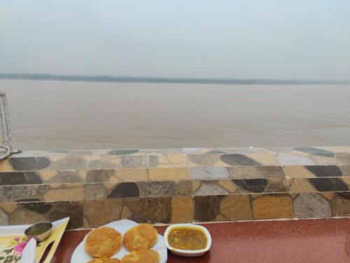 a table with two plates of food next to the water at Shiva Ganges View Guest House in Varanasi